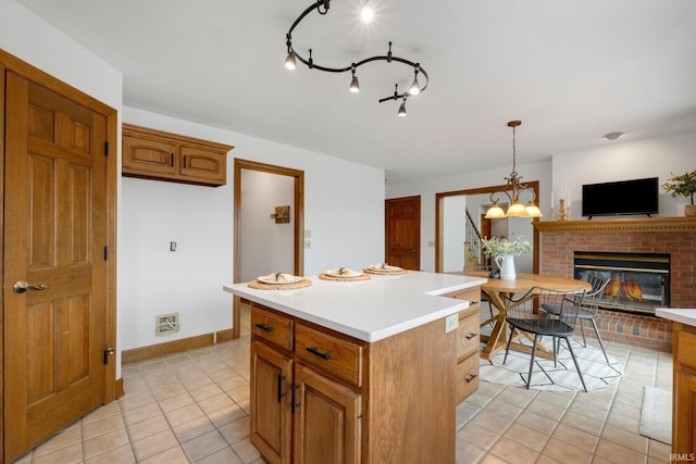 kitchen with light tile patterned floors, brown cabinetry, a center island, light countertops, and a fireplace