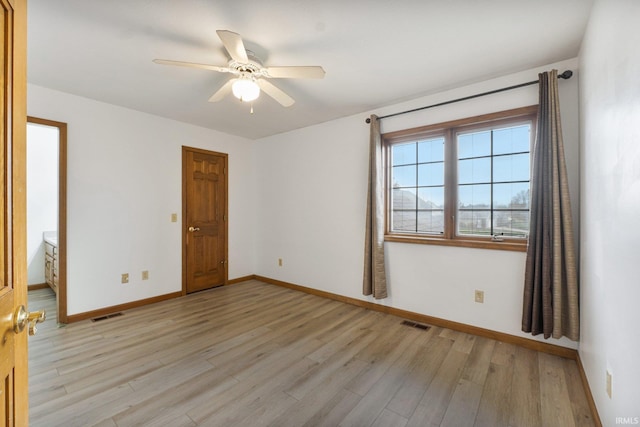 empty room featuring light wood-style flooring, visible vents, ceiling fan, and baseboards