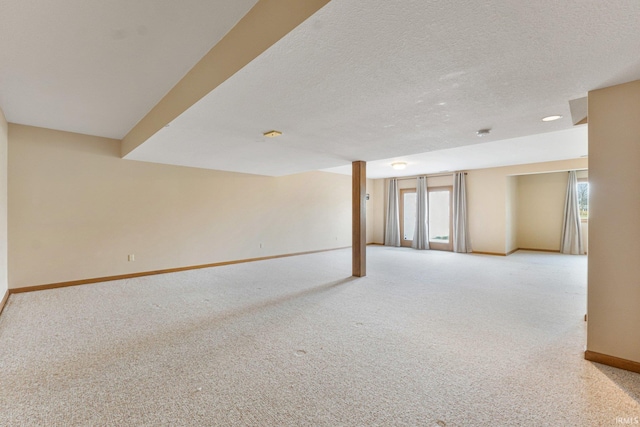 empty room with light carpet, a textured ceiling, and baseboards