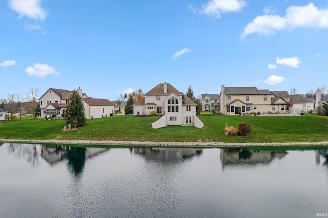 rear view of property with a residential view, a water view, and a yard