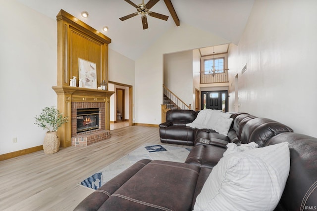 living room with high vaulted ceiling, wood finished floors, baseboards, a brick fireplace, and beam ceiling