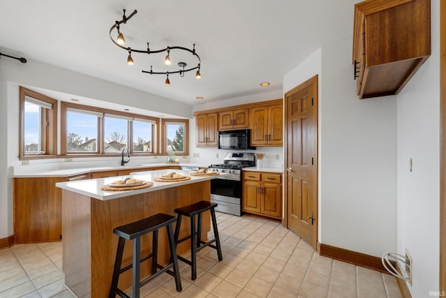 kitchen featuring brown cabinetry, a kitchen island, a breakfast bar, black microwave, and gas stove