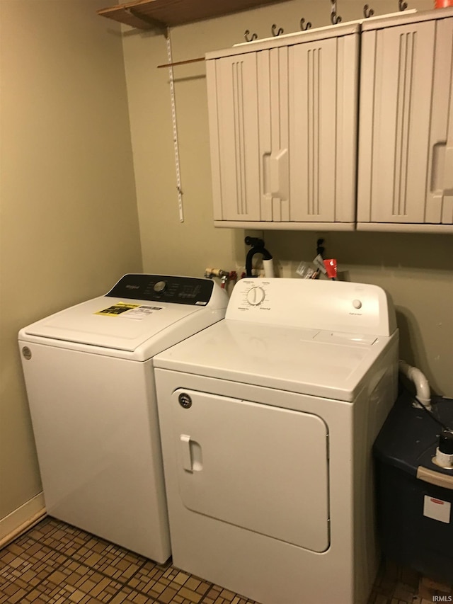 clothes washing area featuring washing machine and dryer and cabinet space