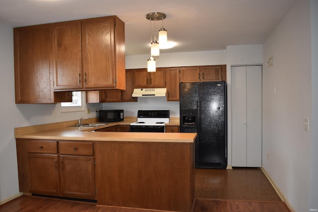 kitchen with brown cabinets, a peninsula, under cabinet range hood, black appliances, and a sink