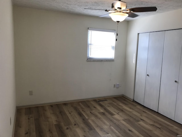 unfurnished bedroom with a ceiling fan, a closet, a textured ceiling, and wood finished floors