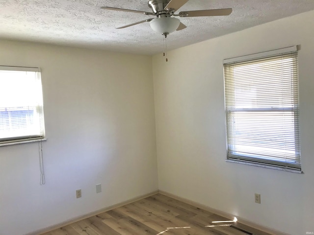 unfurnished room with a textured ceiling, baseboards, light wood-style flooring, and a ceiling fan