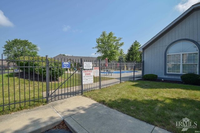 surrounding community featuring a swimming pool, a gate, fence, and a lawn