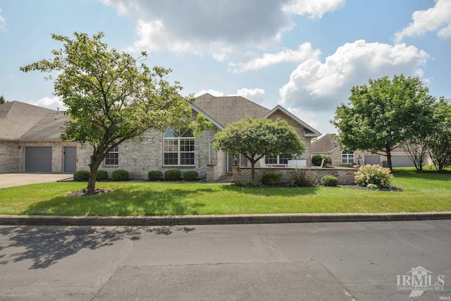 view of front of home featuring driveway, brick siding, an attached garage, and a front yard