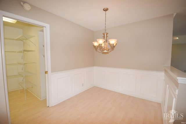 spare room featuring a chandelier, wainscoting, and light wood-style floors