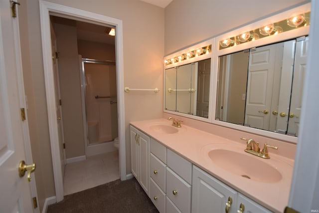 full bathroom with double vanity, a sink, a shower with door, and baseboards