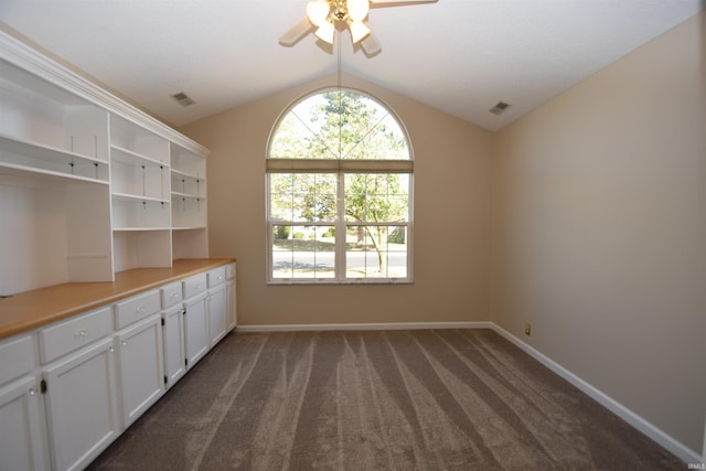 interior space featuring vaulted ceiling, dark carpet, visible vents, and baseboards