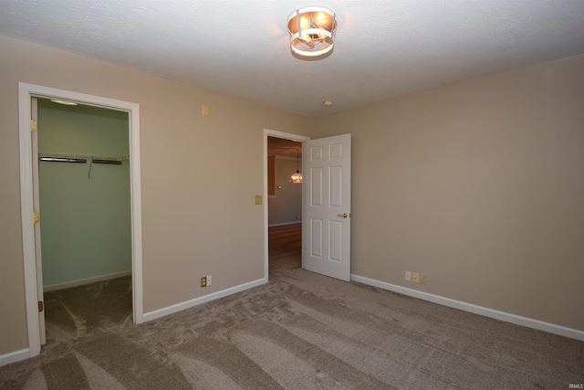 unfurnished bedroom with carpet, a spacious closet, baseboards, and a closet