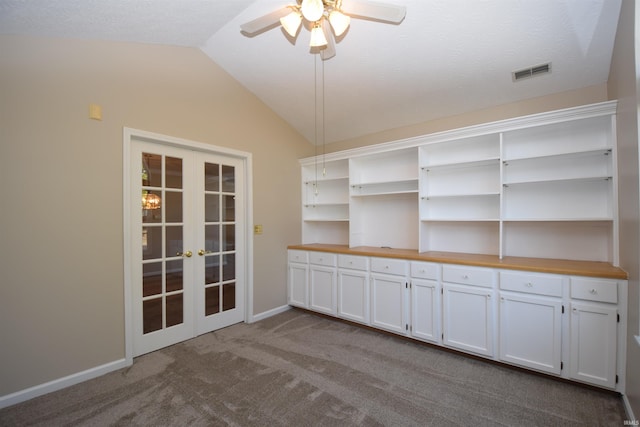 interior space featuring baseboards, visible vents, vaulted ceiling, dark colored carpet, and french doors