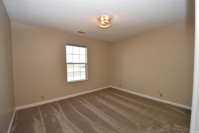 unfurnished room featuring carpet floors, visible vents, and baseboards