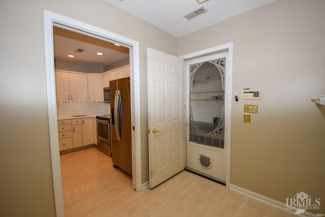 kitchen featuring light countertops, appliances with stainless steel finishes, light wood-style flooring, and visible vents