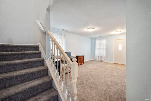 stairway with a wealth of natural light, carpet, and baseboards