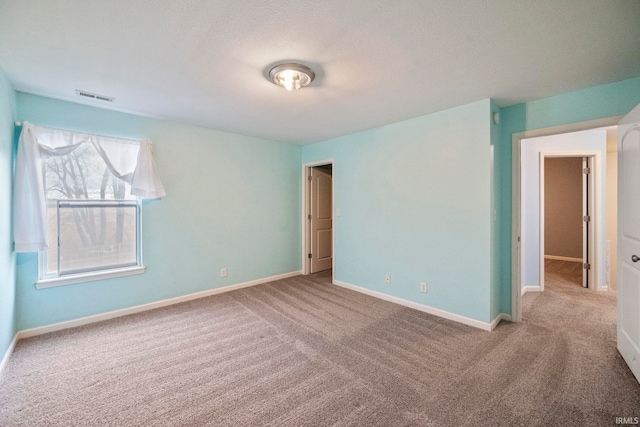 empty room with carpet floors, visible vents, and baseboards