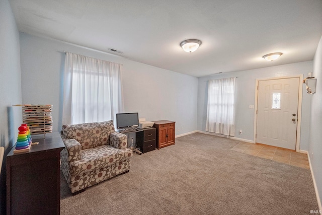 sitting room with baseboards, visible vents, and light colored carpet