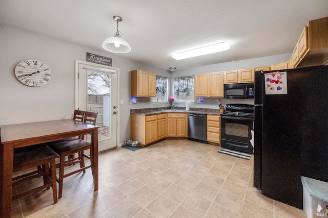 kitchen with dark countertops, hanging light fixtures, light brown cabinetry, a sink, and black appliances