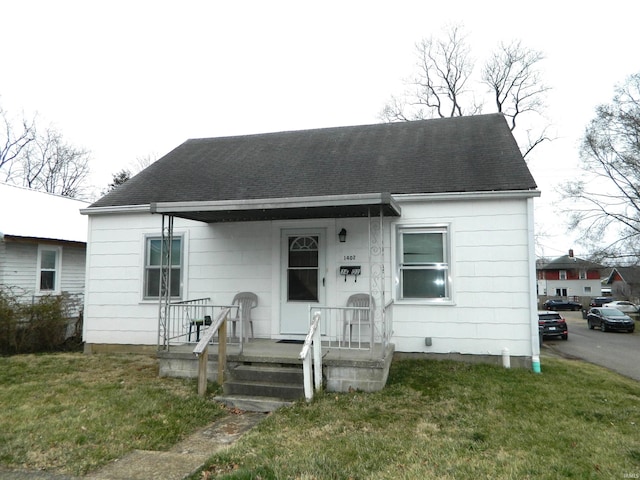 bungalow with a porch, a front yard, and roof with shingles