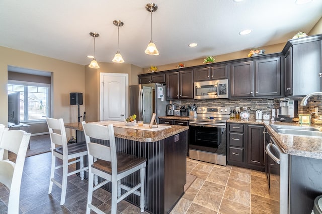 kitchen featuring tasteful backsplash, a kitchen breakfast bar, a center island, stainless steel appliances, and a sink