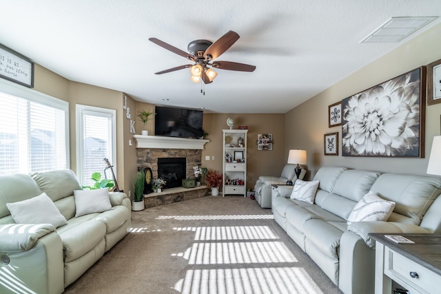 carpeted living area with a fireplace, visible vents, and a ceiling fan