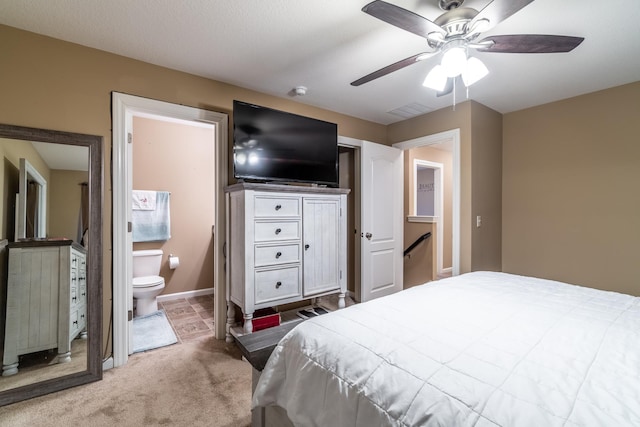 carpeted bedroom featuring baseboards, visible vents, ceiling fan, and ensuite bath