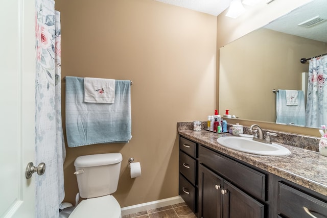 full bathroom with toilet, vanity, visible vents, and baseboards