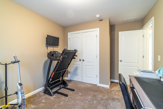 workout room featuring carpet, visible vents, a textured ceiling, and baseboards