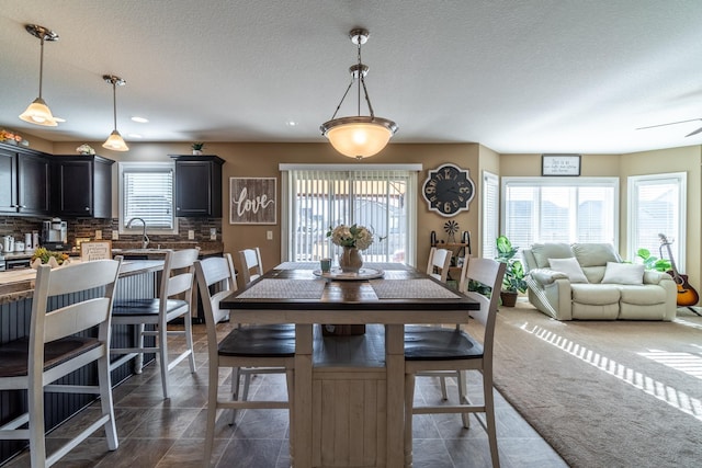 dining area with a textured ceiling, dark colored carpet, and dark tile patterned flooring