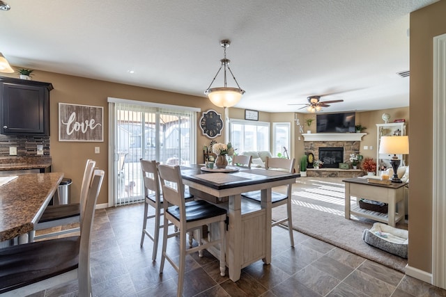 dining room with baseboards, a fireplace, visible vents, and a ceiling fan