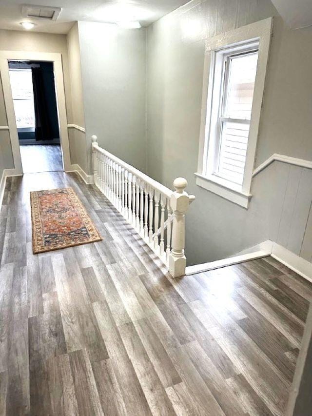 corridor featuring baseboards, an upstairs landing, and wood finished floors