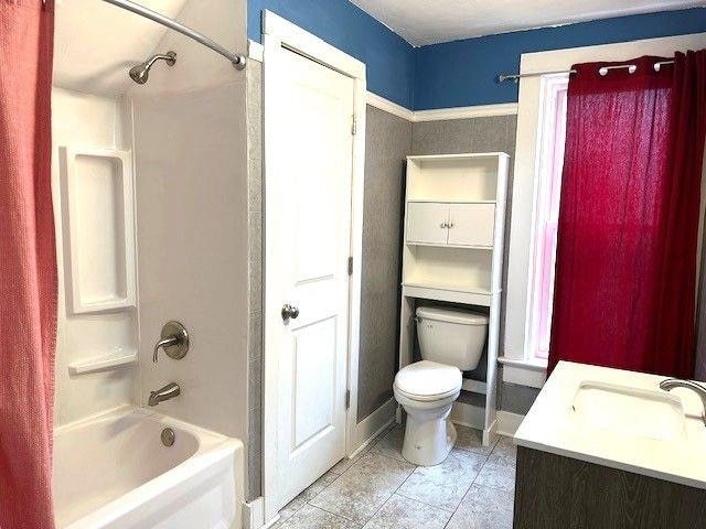 full bath featuring washtub / shower combination, baseboards, toilet, and tile patterned floors