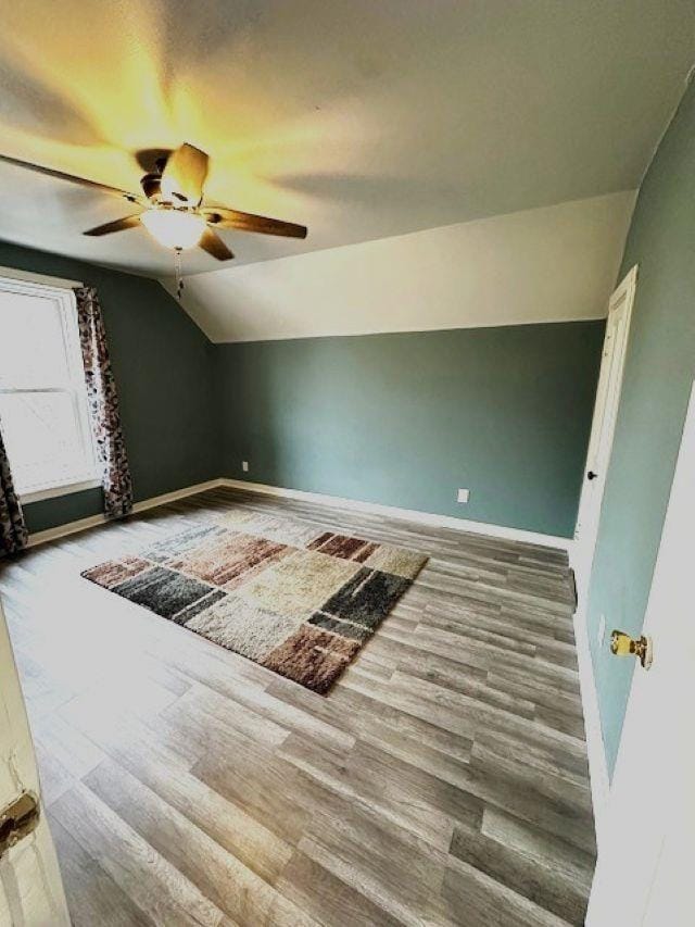 additional living space with a ceiling fan, baseboards, vaulted ceiling, and wood finished floors