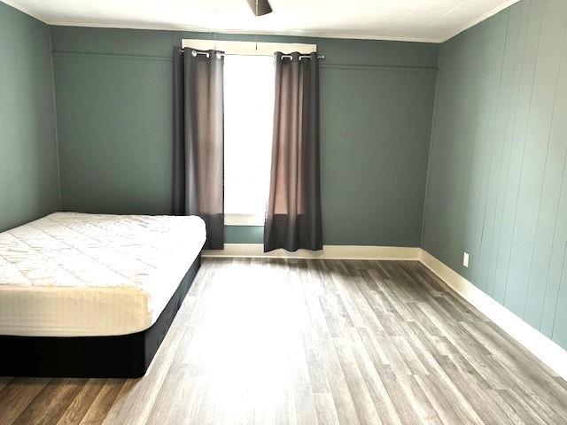 bedroom featuring ornamental molding, baseboards, and wood finished floors