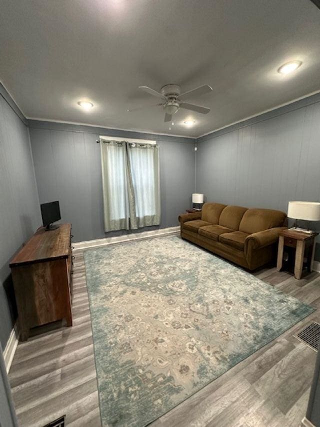 living room featuring wood finished floors, a ceiling fan, and crown molding