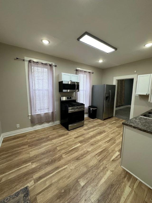 kitchen with recessed lighting, stainless steel appliances, white cabinetry, baseboards, and light wood-style floors