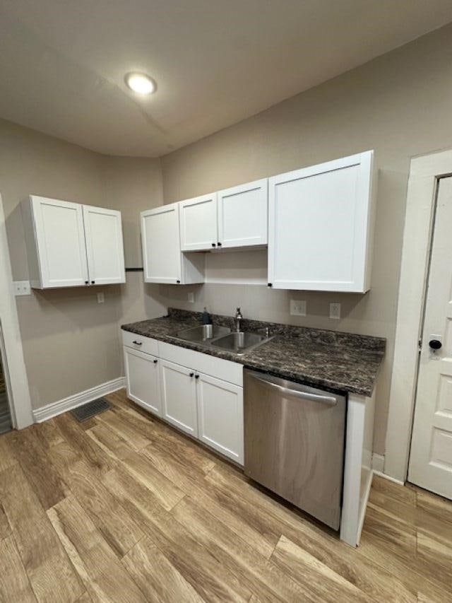 kitchen featuring white cabinetry, a sink, light wood finished floors, and stainless steel dishwasher