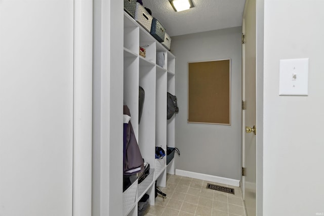 mudroom featuring baseboards, visible vents, a textured ceiling, and light tile patterned flooring