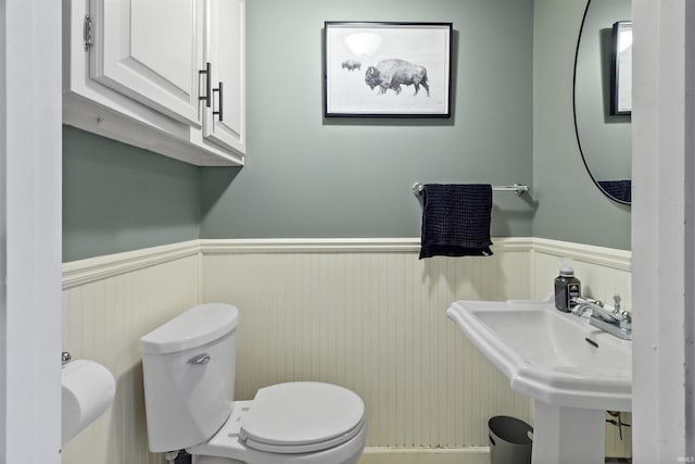 bathroom featuring a wainscoted wall, a sink, and toilet