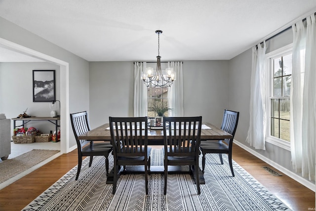 dining room with a notable chandelier, visible vents, dark wood-style flooring, and a wealth of natural light