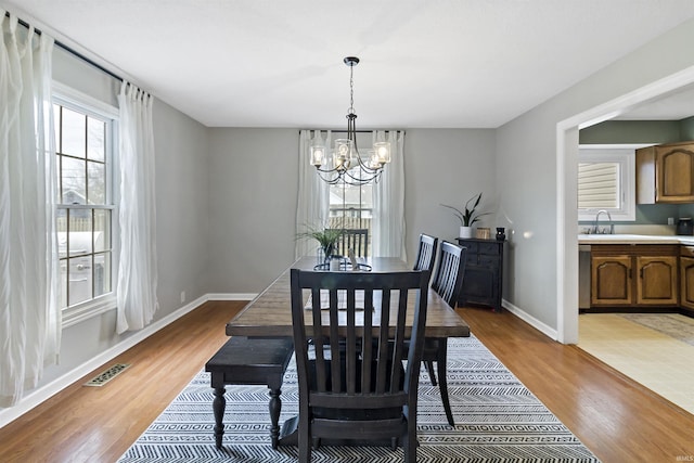 dining area with a chandelier, light wood-style flooring, plenty of natural light, and visible vents