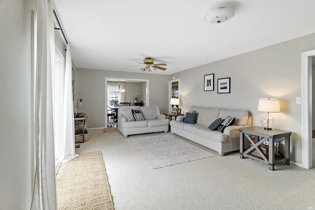 carpeted living room featuring a ceiling fan and baseboards