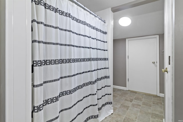 full bath featuring a shower with shower curtain and baseboards