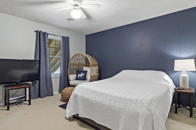 bedroom with a ceiling fan, carpet flooring, visible vents, and a textured ceiling