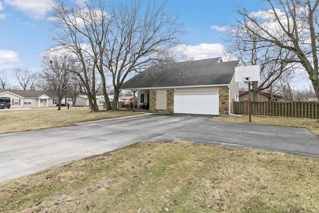 view of property exterior with driveway, a garage, stone siding, fence, and a yard