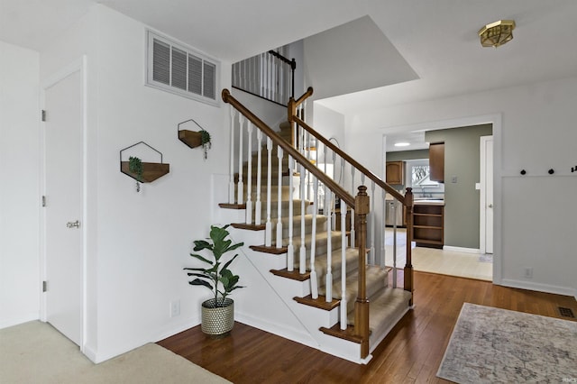 staircase featuring baseboards, visible vents, and wood finished floors