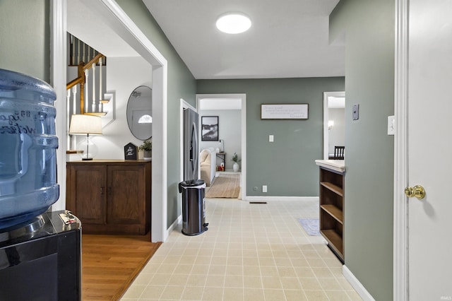 hallway featuring stairs, light wood-style floors, and baseboards