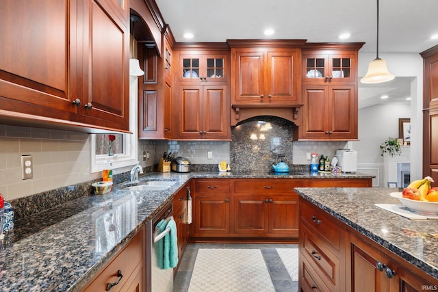 kitchen with glass insert cabinets, a sink, decorative light fixtures, and custom range hood