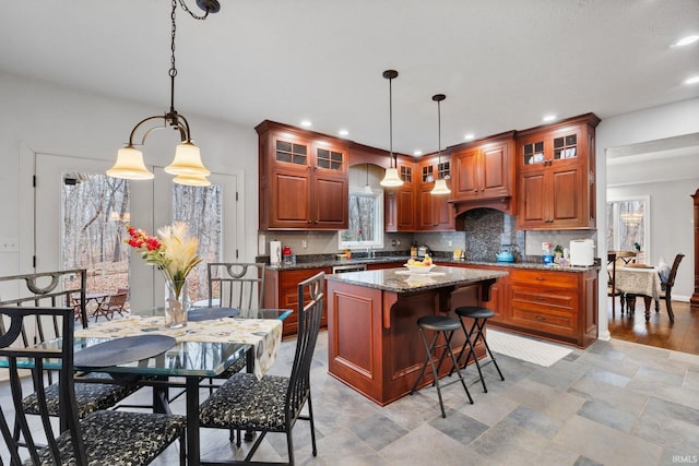 kitchen with glass insert cabinets, a breakfast bar, backsplash, and a center island